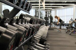 Visuel d'une salle de sport, haltères au premier plan.